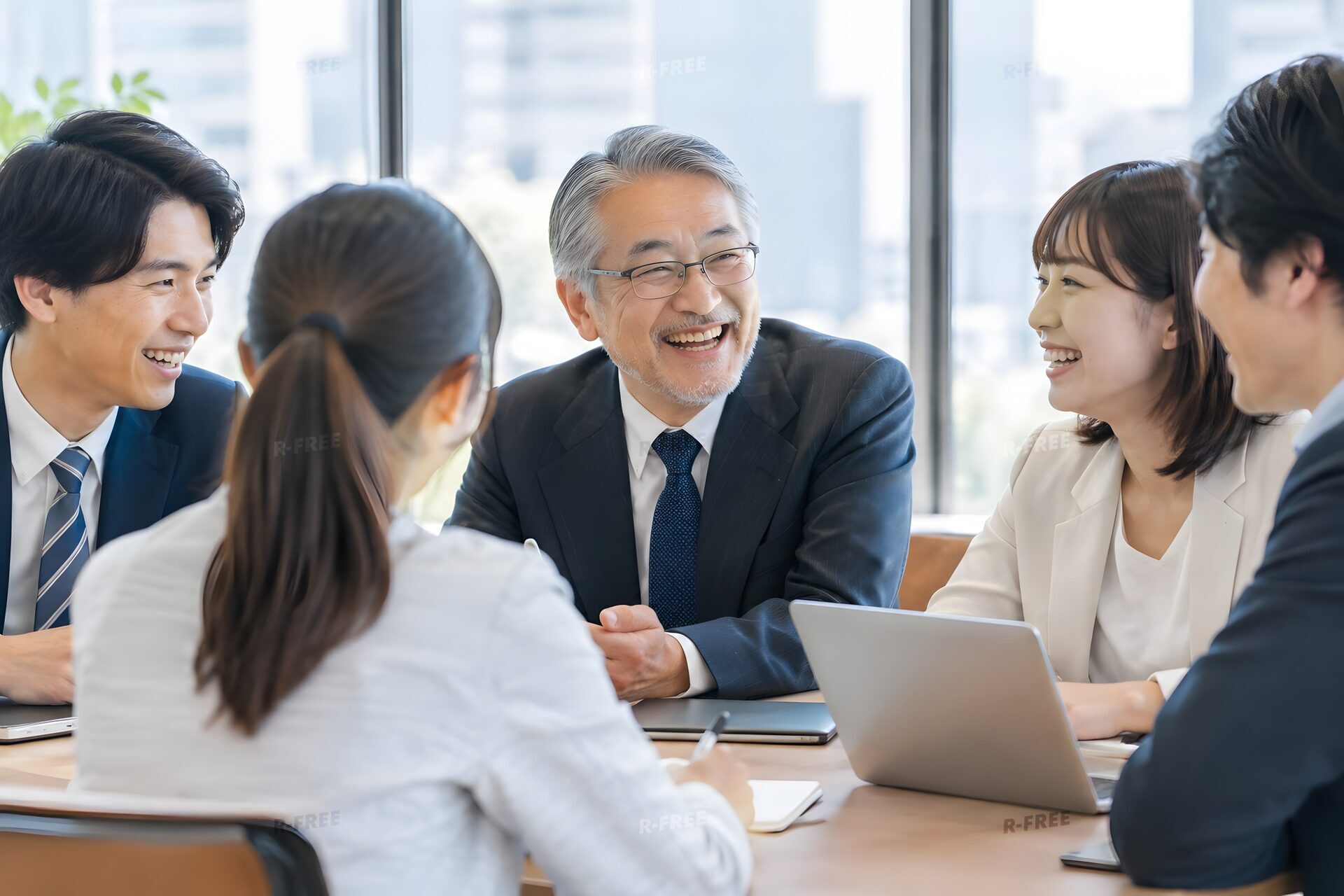 会議室で若手と笑い合う60代の社員