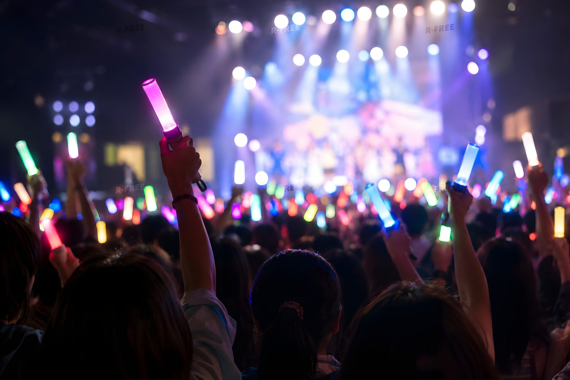 暗いライブ会場でペンライトを振るファンたち