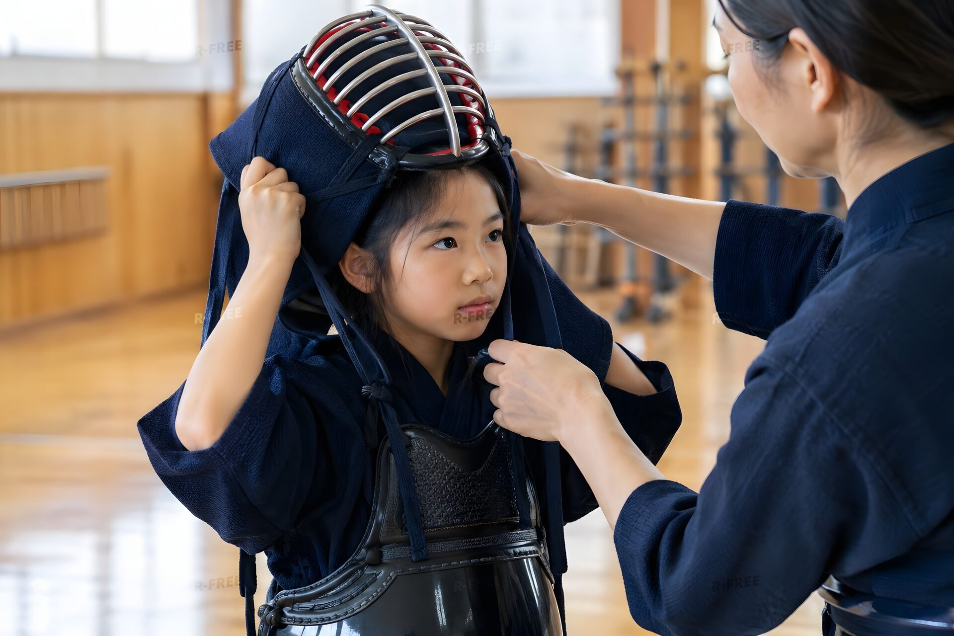 道場で先生に手伝ってもらい面をつける小学生
