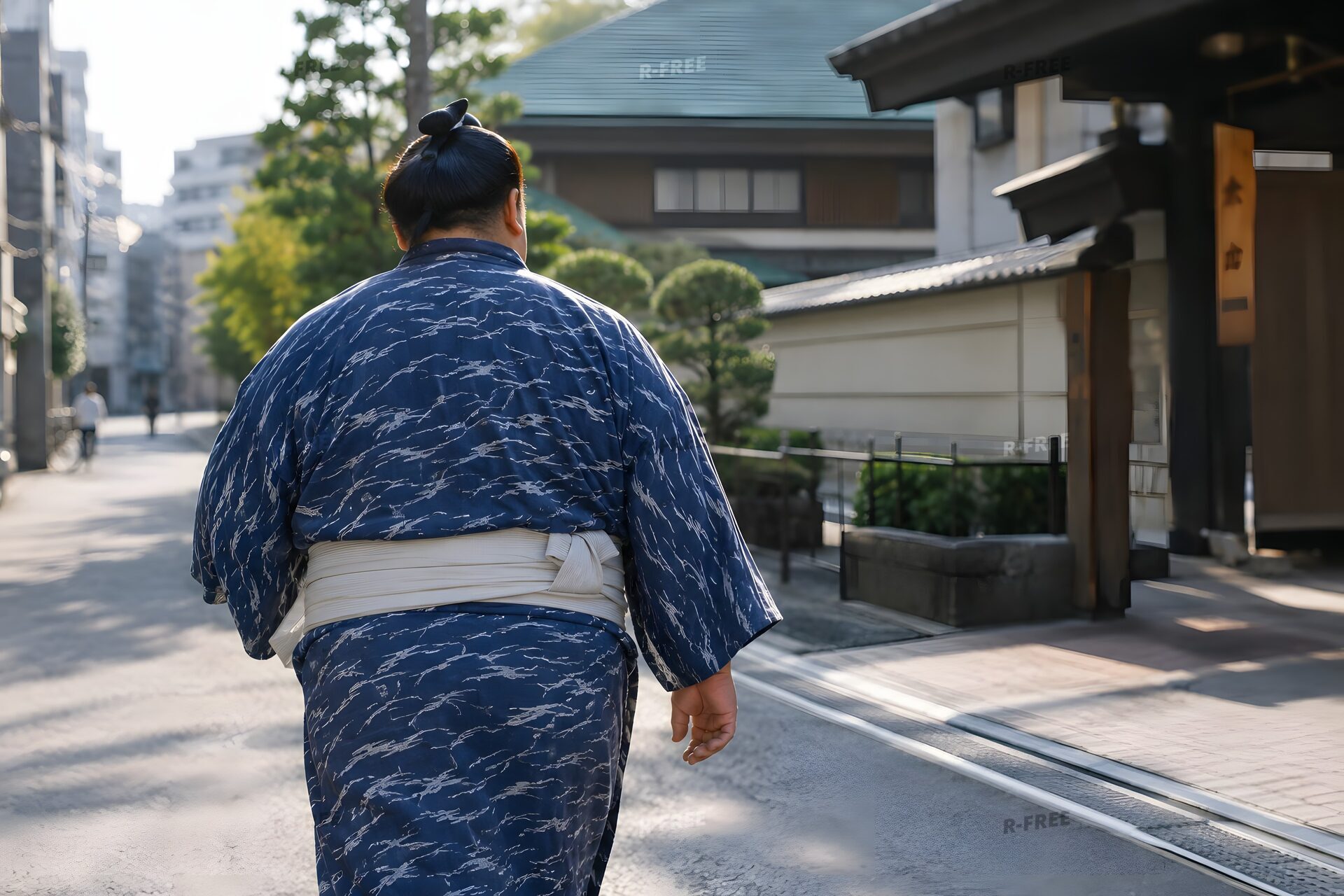 朝の街を浴衣姿で歩く髷を結った力士の後ろ姿