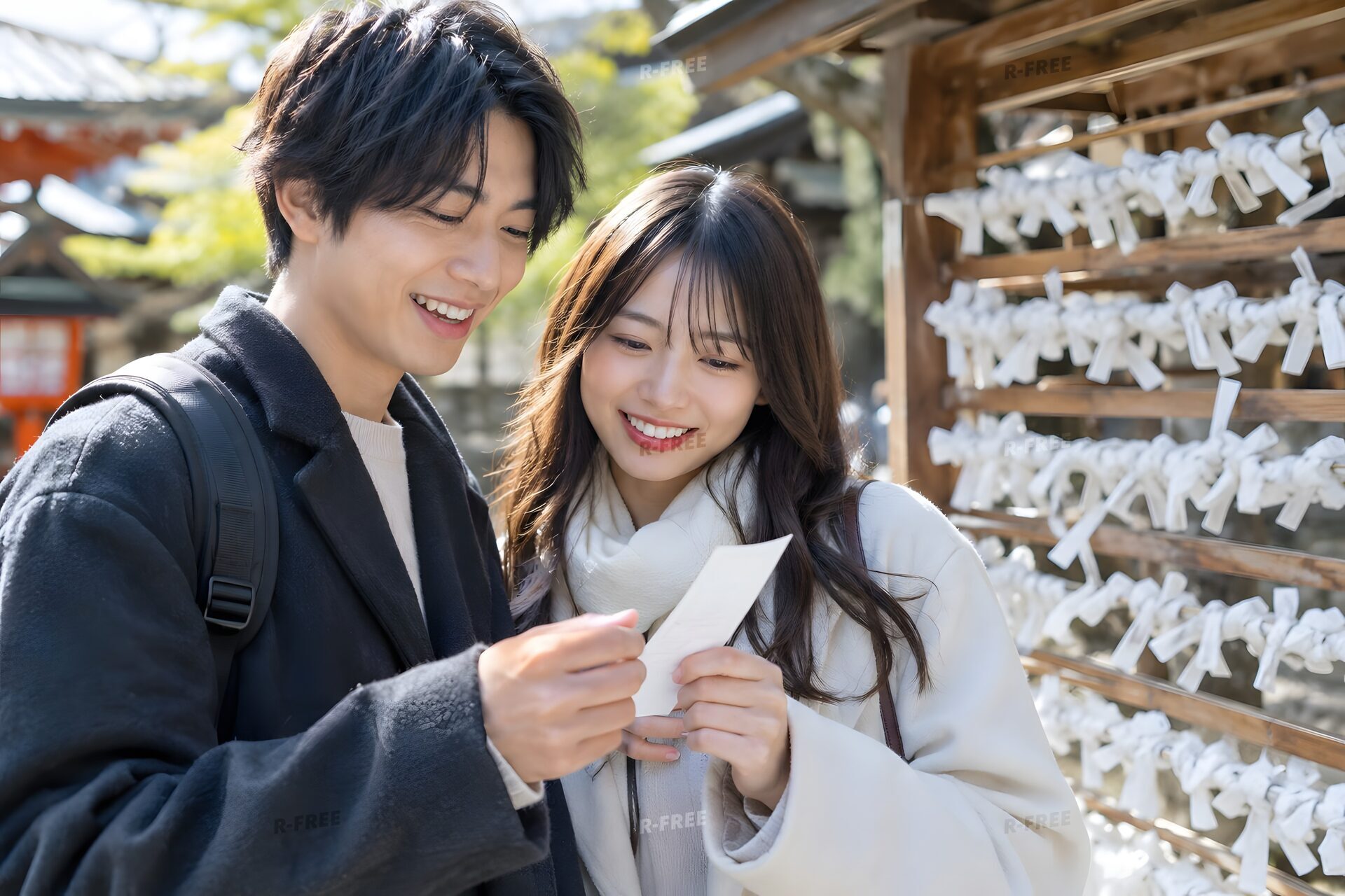 神社でおみくじを読んで笑い合う若いカップル