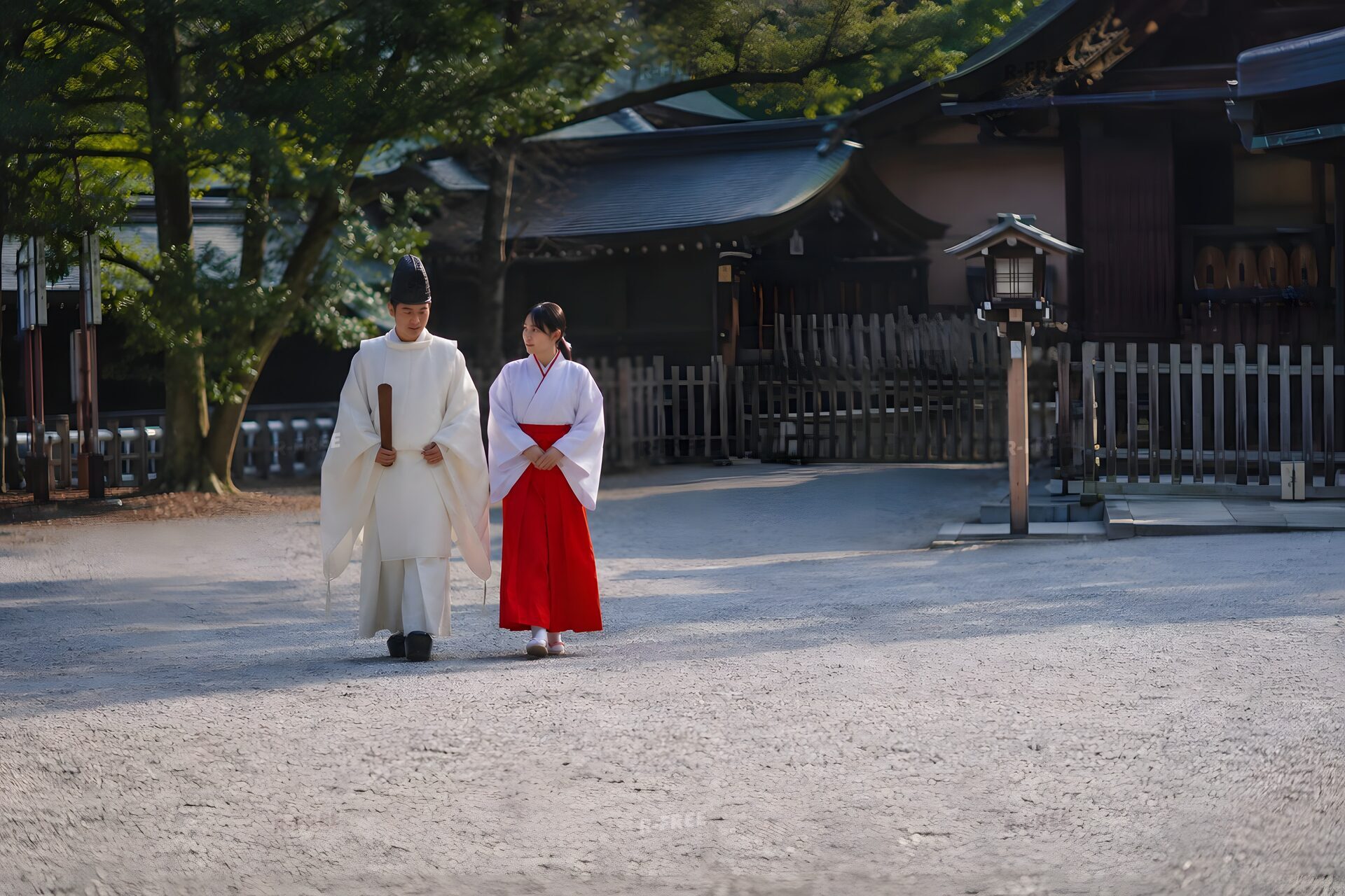 朝の境内を並んで歩く神職と巫女