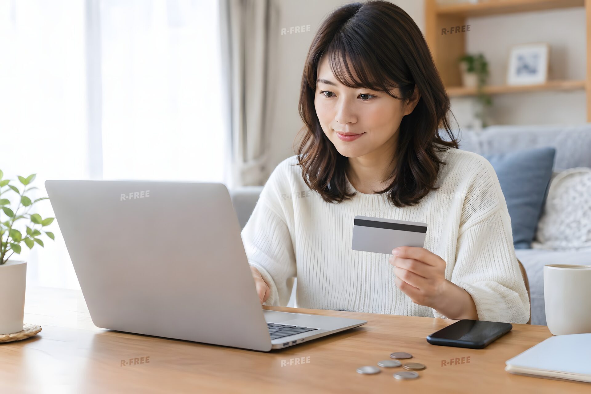 カードを手にネットで買い物をする30代女性