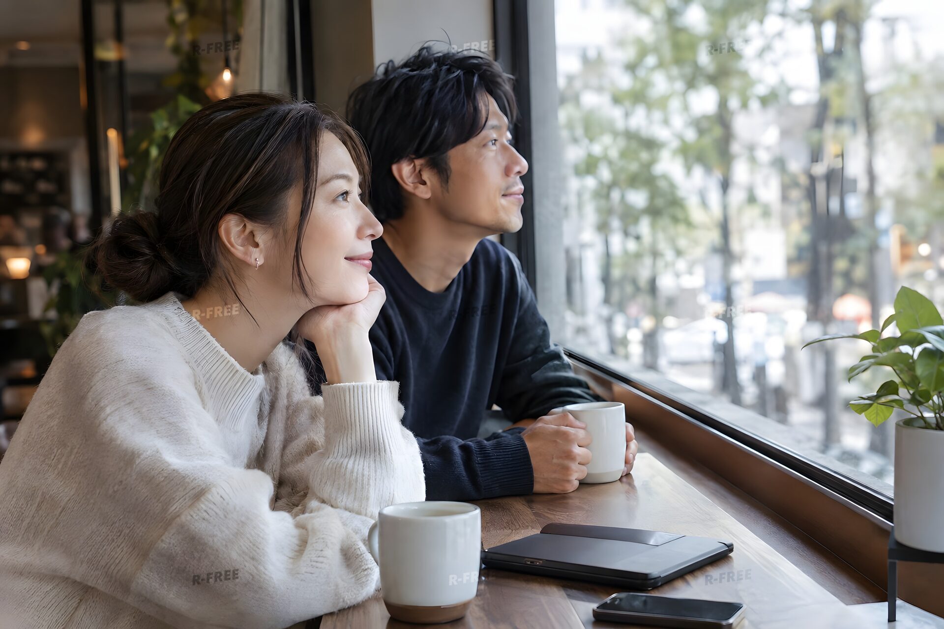 カフェの窓際に並んで座る30代のカップル