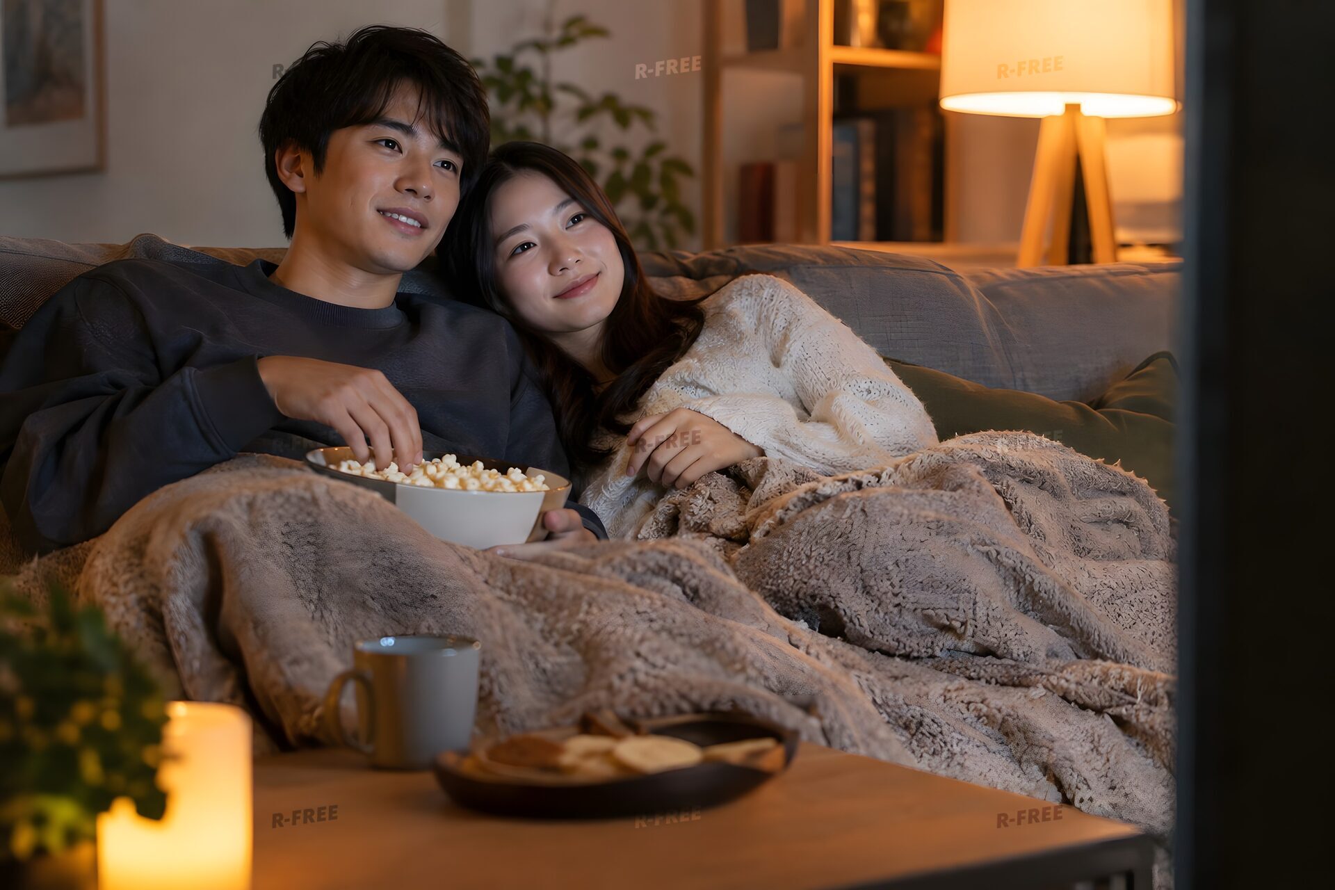 家のソファで映画を見るカップル