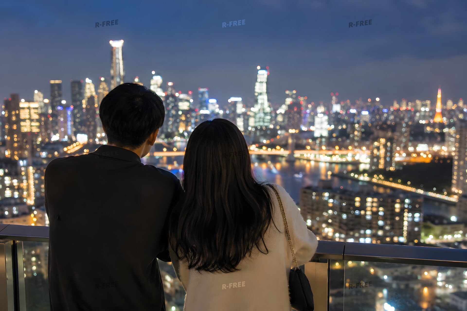 街の夜景を眺めるカップルの後ろ姿