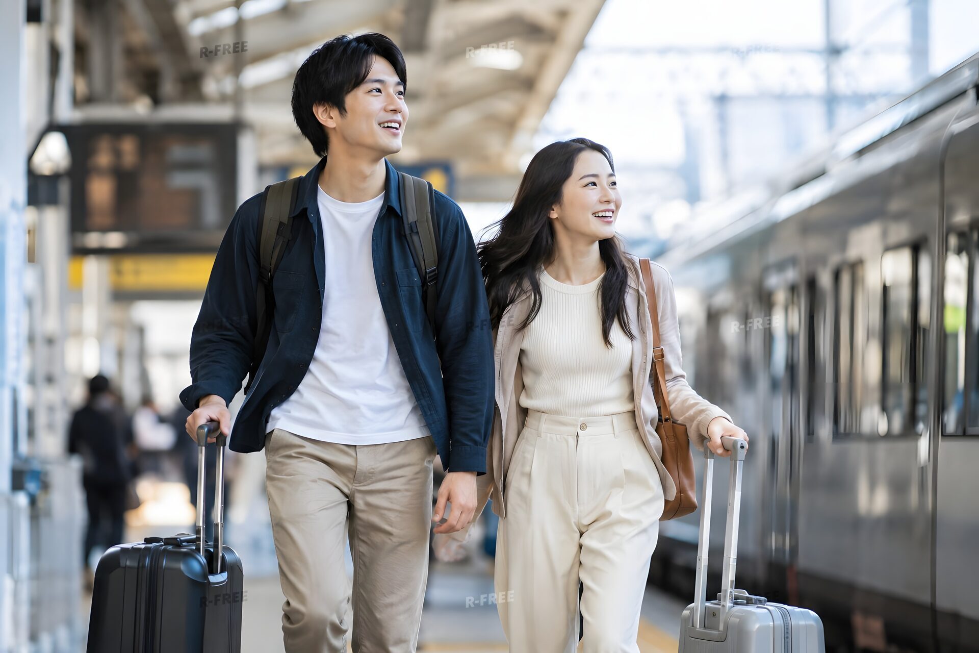 スーツケースを引いて駅を歩くカップル