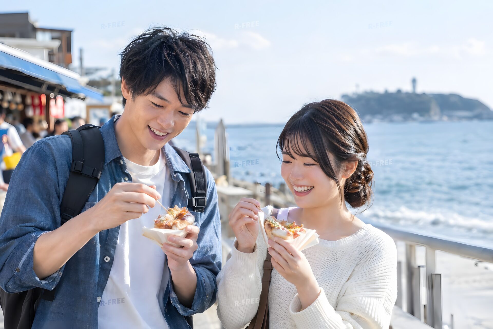 海辺の観光地で食べ歩きをするカップル