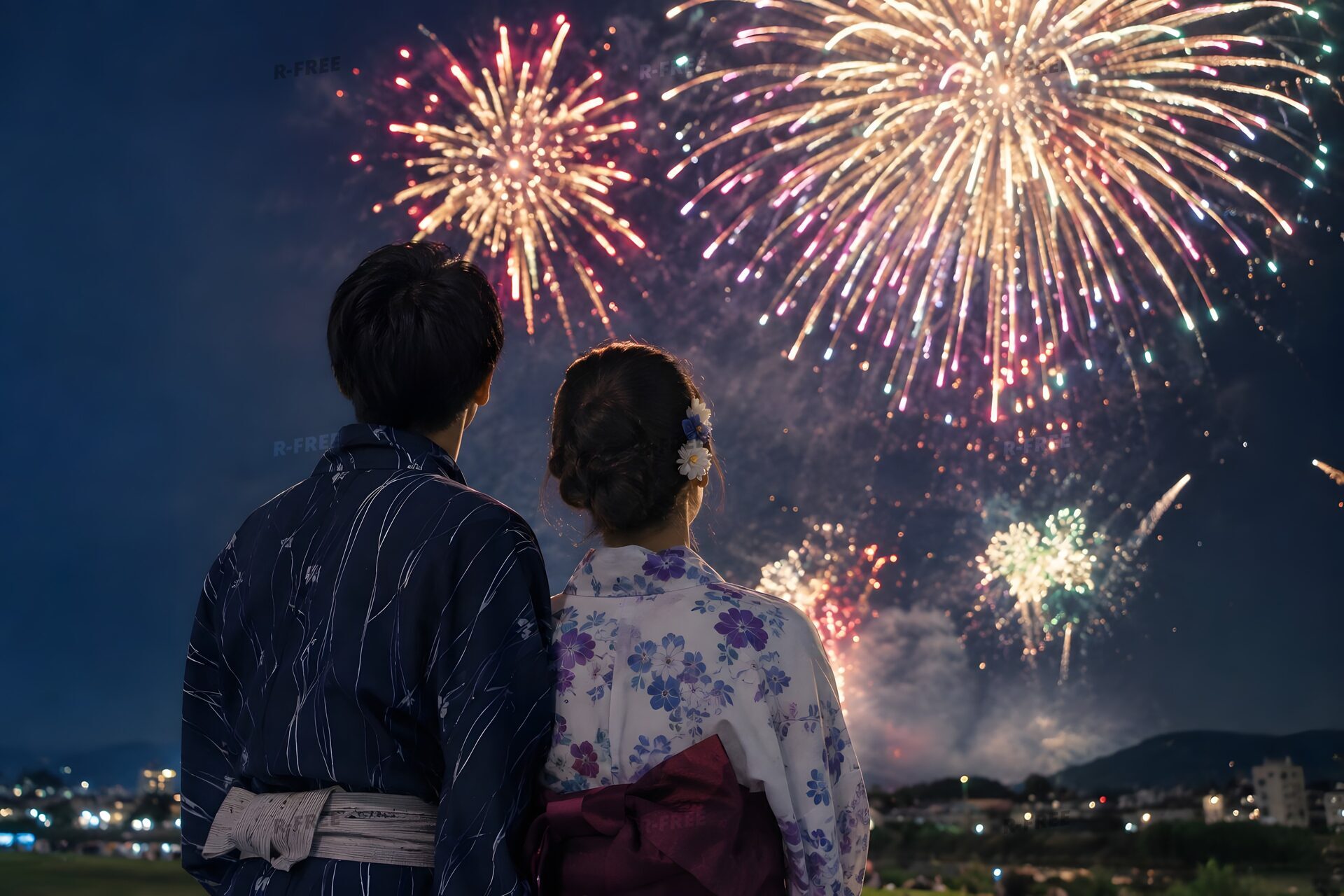 浴衣で花火を見上げるカップルの後ろ姿