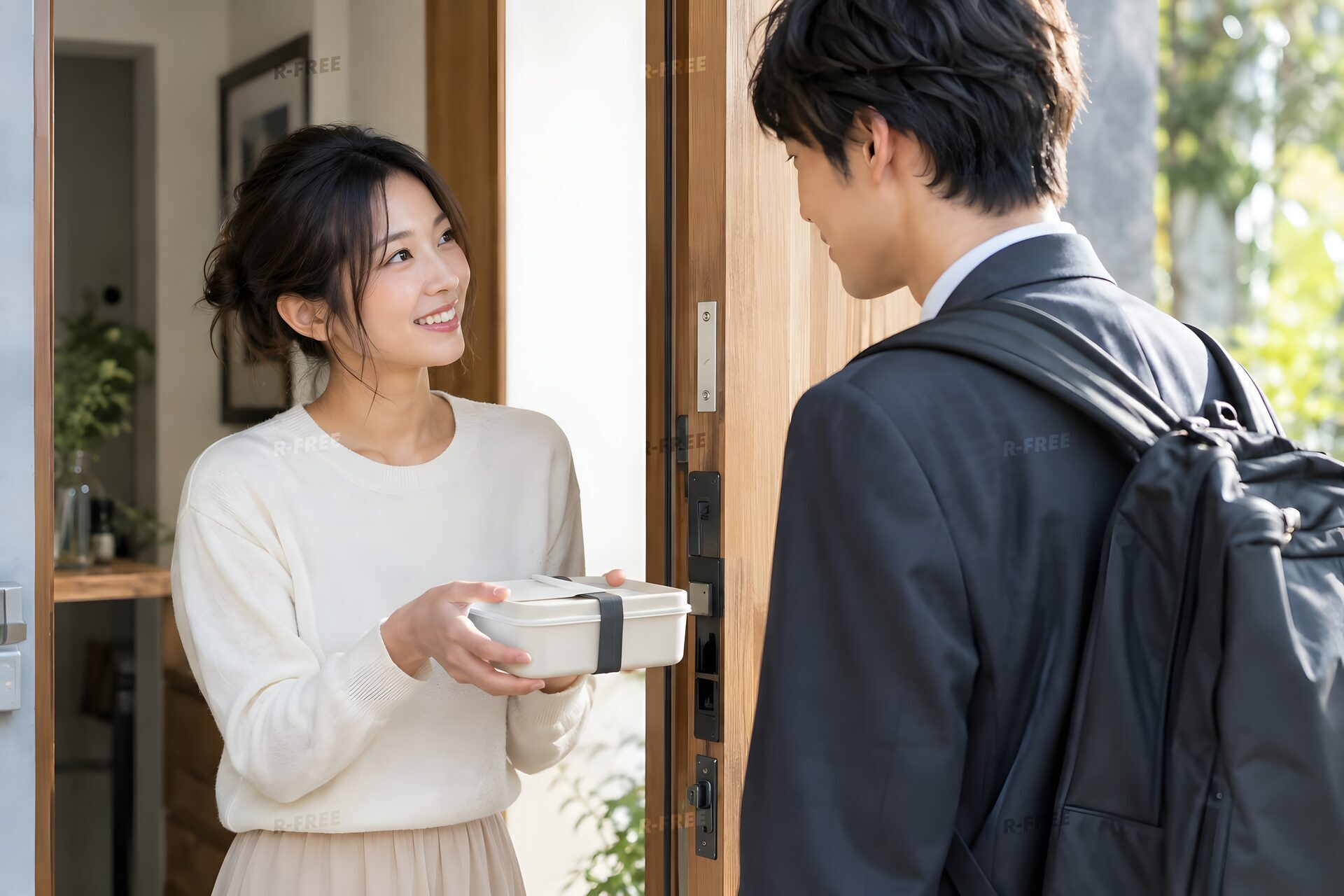 朝の玄関で夫を見送る新婚の妻
