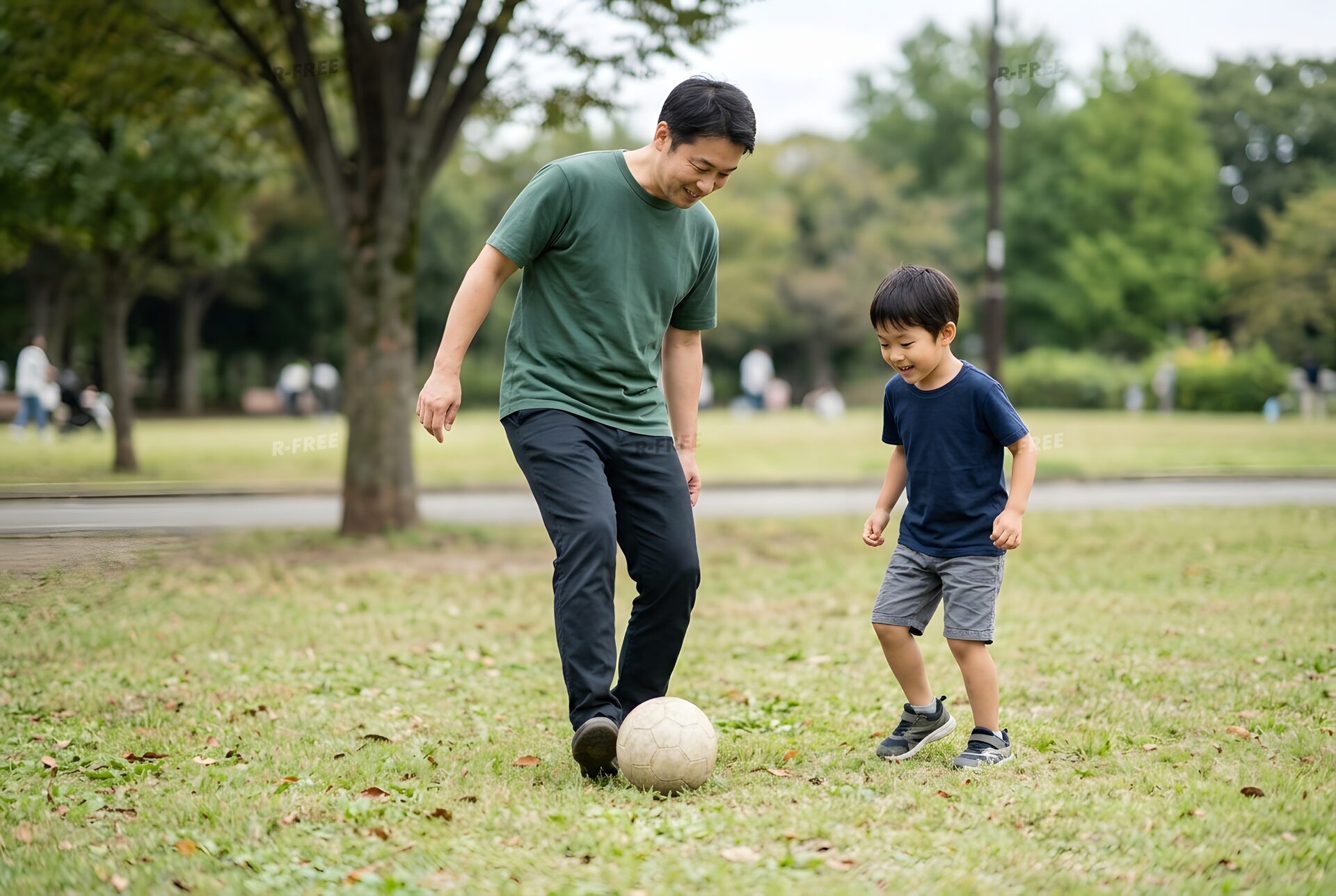 公園で息子にボールの蹴り方を教える父親