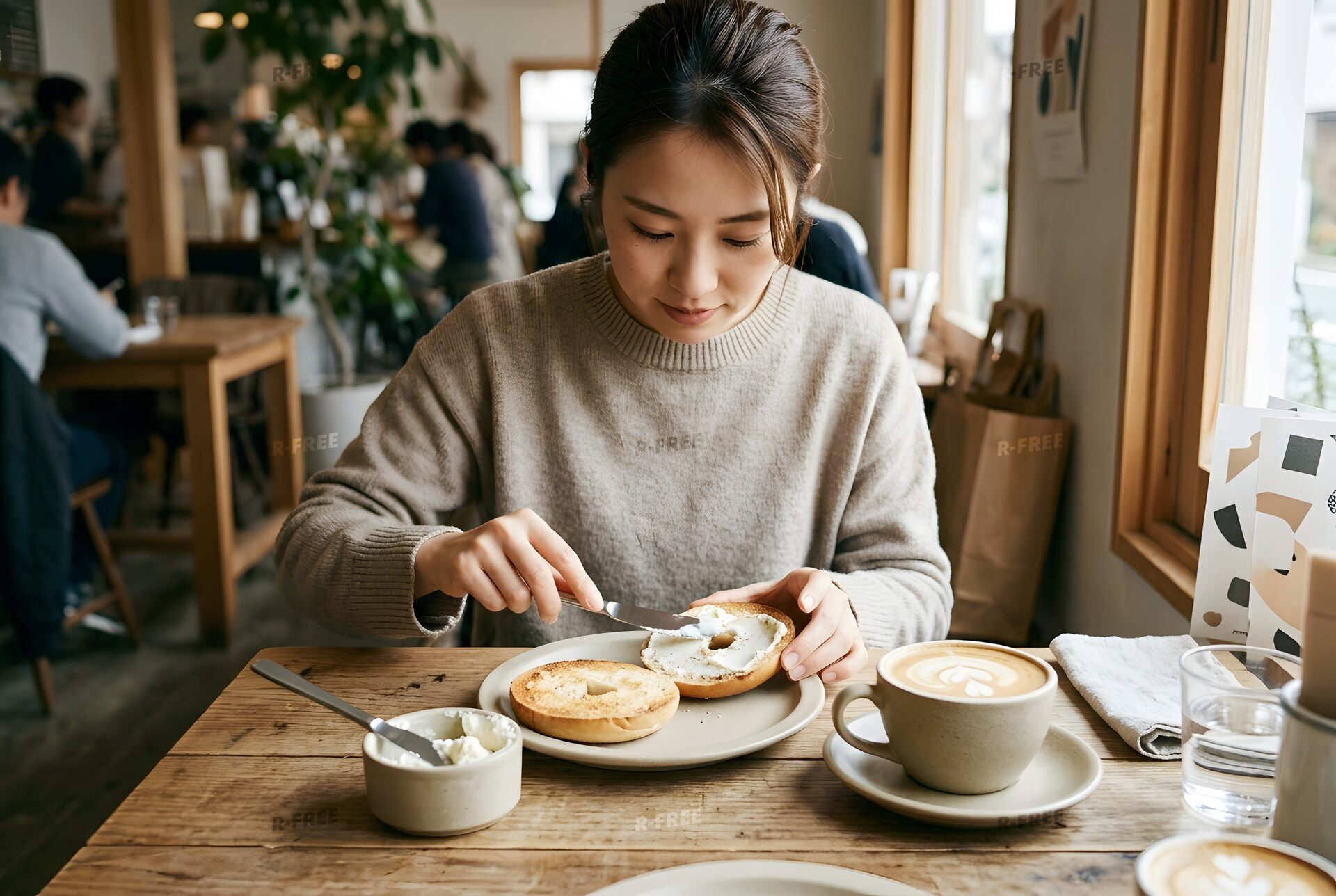 ベーグルにクリームチーズを塗る女性