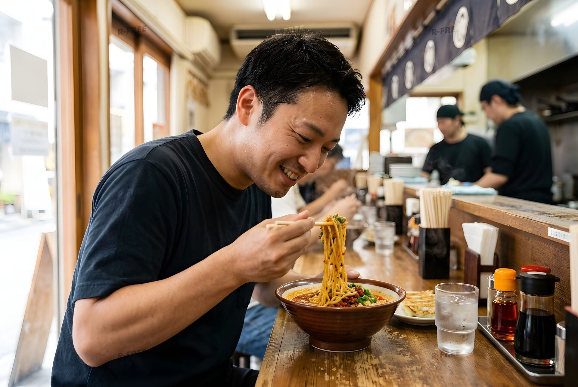 汗をかきながら担々麺を食べる男性