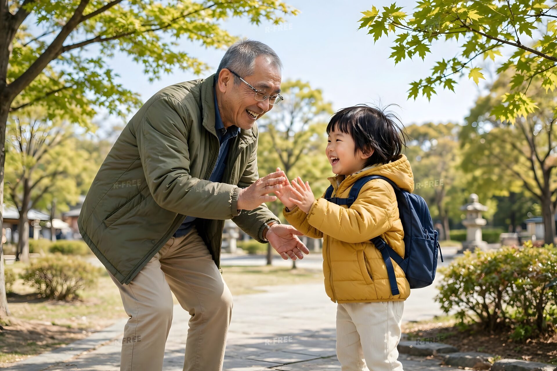 公園で孫と手を合わせて遊ぶ祖父