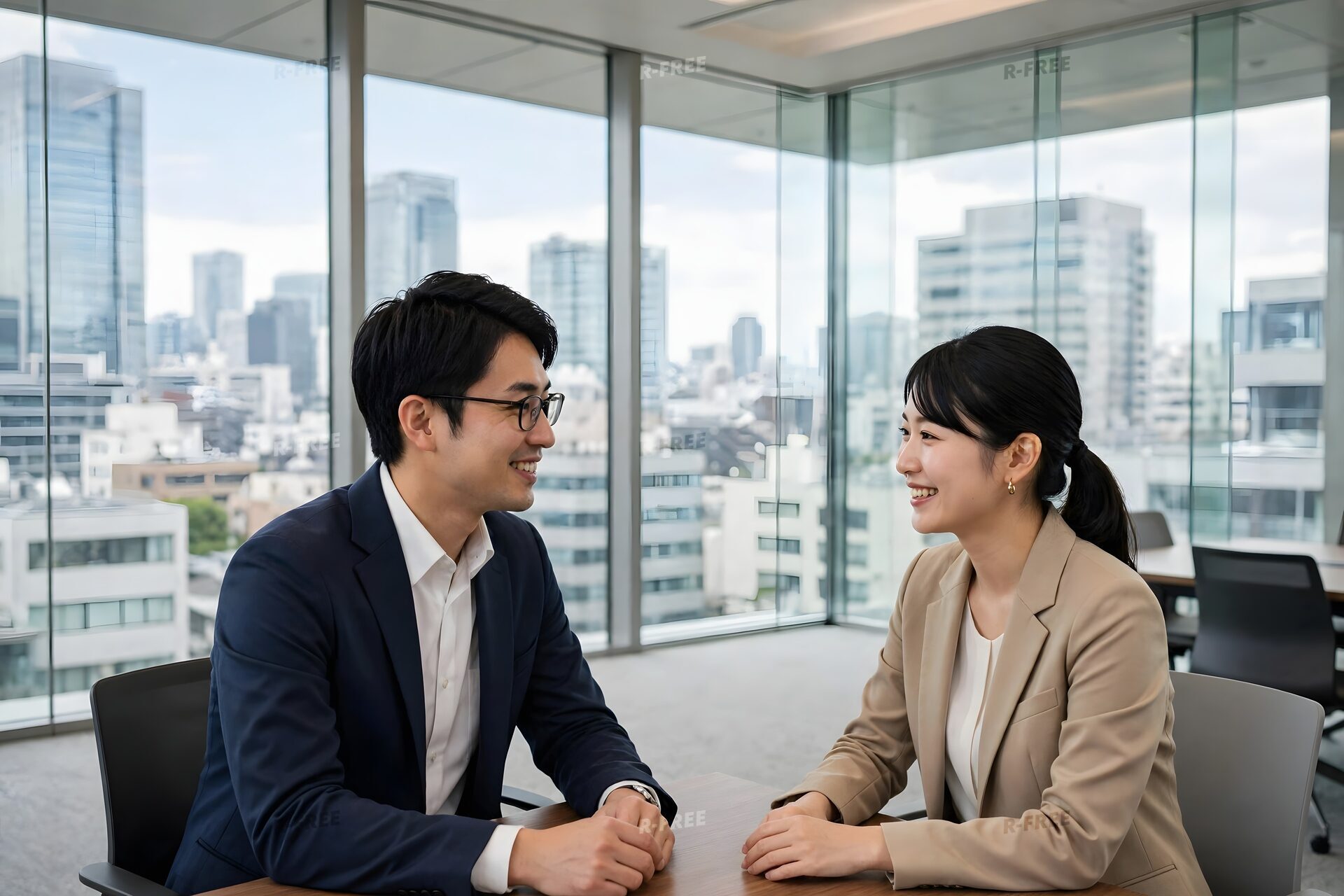 ガラス張りの会議室で向かい合って話す男女