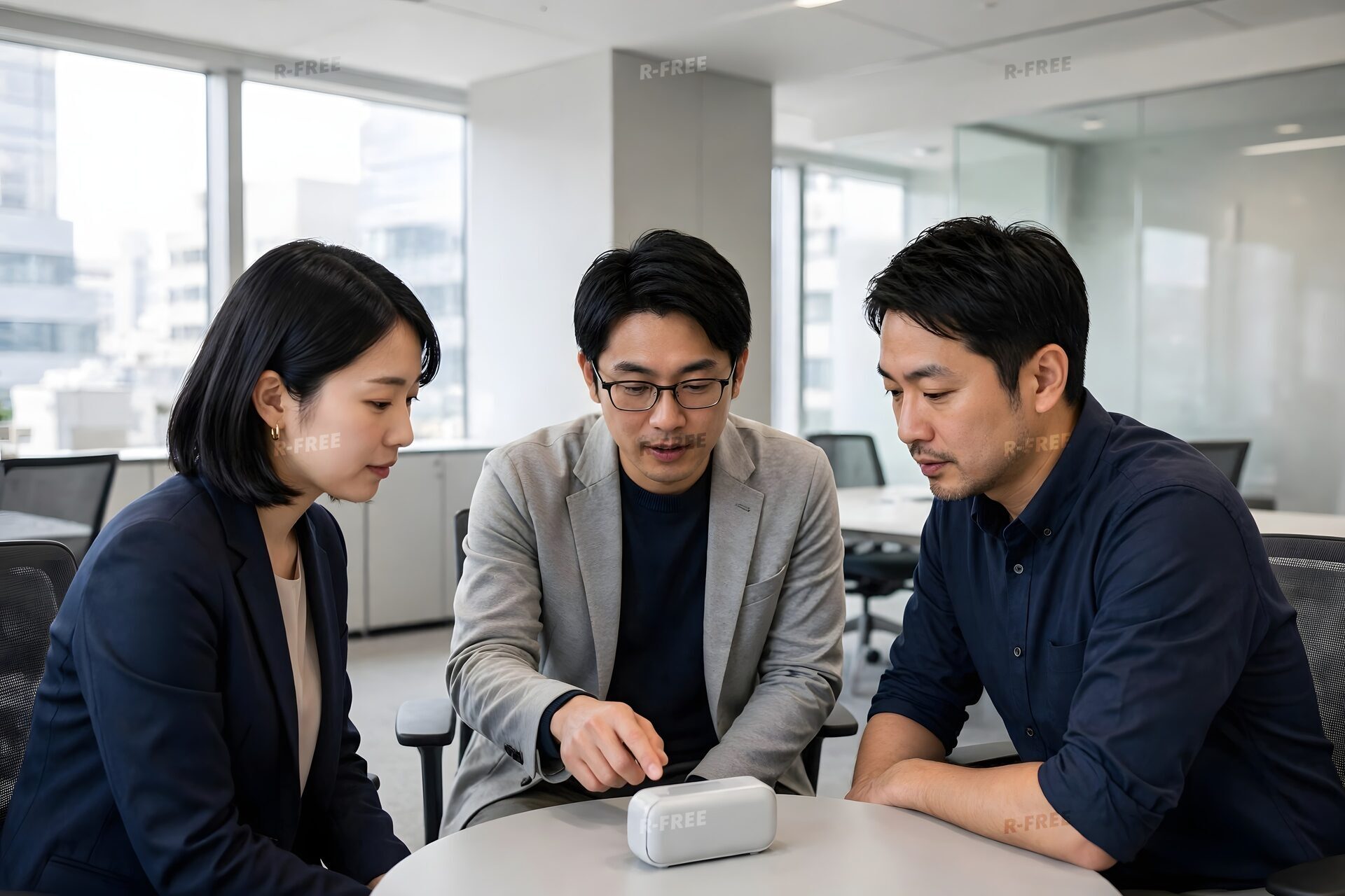 小さな機器を囲んで検討する3人