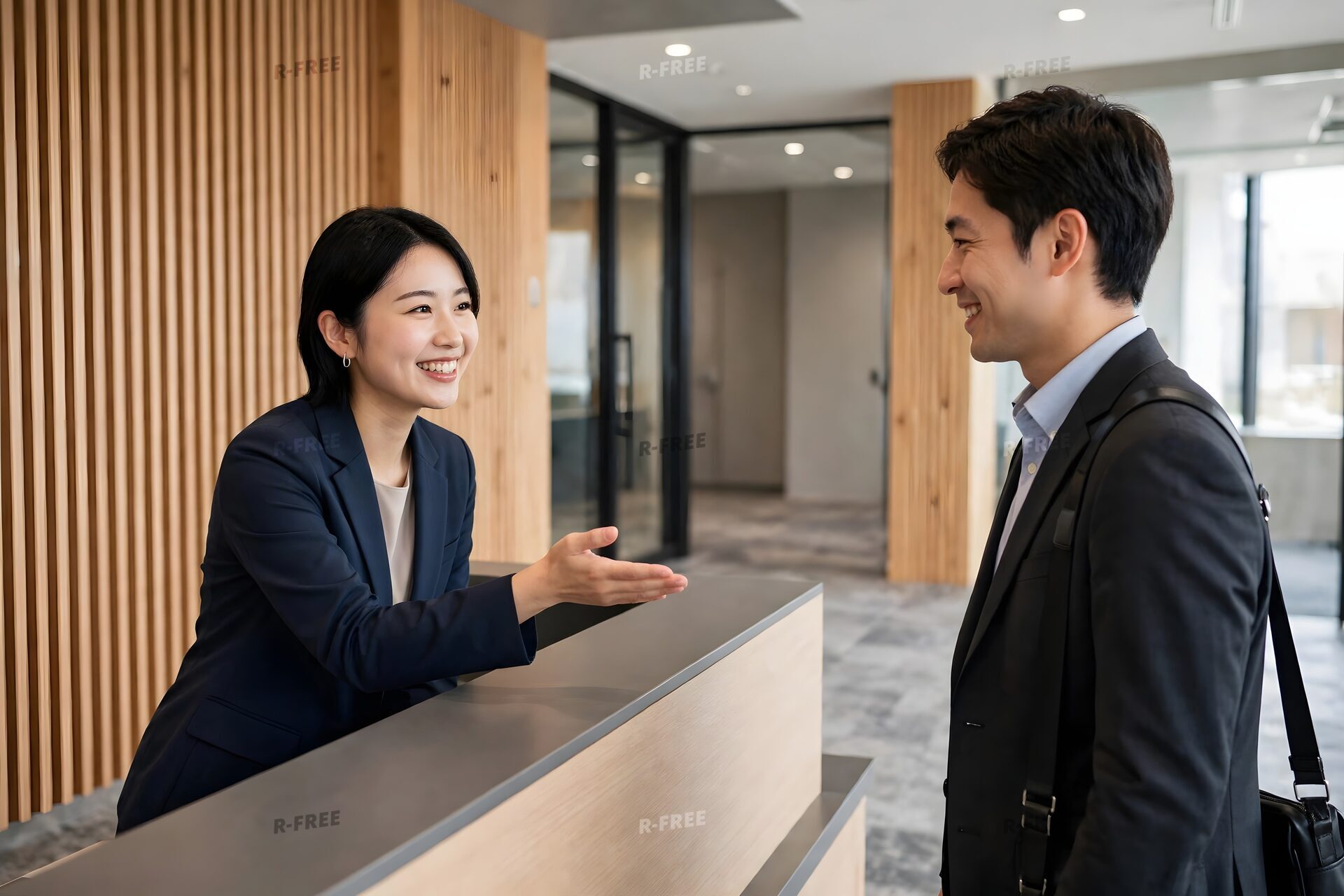 受付で来客を案内する笑顔の女性