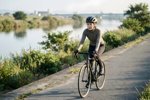 河川敷をロードバイクで走る女性