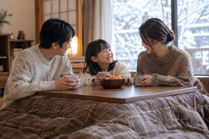 厚着をしてこたつで温まる家族