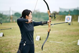 アーチェリーで弓を引く女性