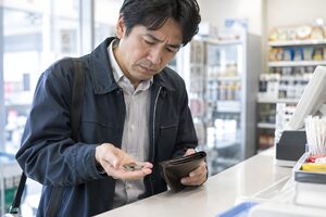 薄い財布から小銭を数える40代男性