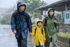 雨の中を避難所へ向かう家族