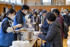 避難所で温かい汁物を配るボランティア