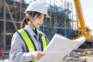 建設現場で図面を確認する20代の女性技術者