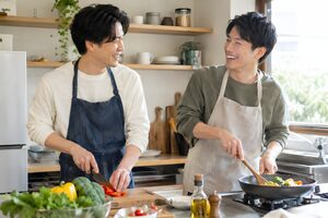 自宅のキッチンで一緒に料理する男性カップル
