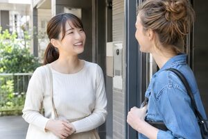 マンションの前であいさつする日本人と外国人の住民