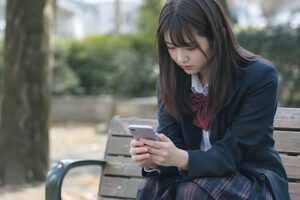 スマホを見て落ち込む女子高生