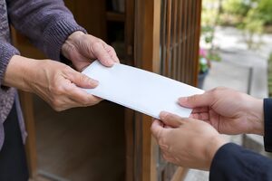 玄関先で現金の封筒を手渡す手元