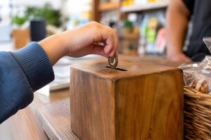 募金箱に硬貨を入れる子どもの手元