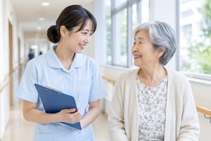 病院の廊下で高齢の女性患者と笑顔で話す看護師