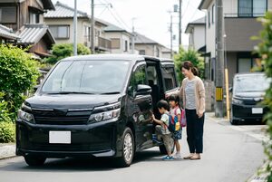 ミニバンのスライドドアを開ける母親