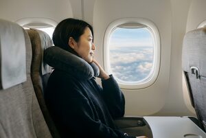 機内の窓から雲を眺める女性