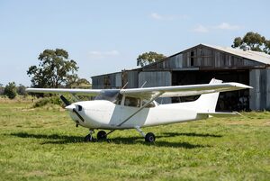 草地の飛行場に停まる小型プロペラ機
