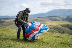 丘の上で離陸の準備をするパラグライダーの男性