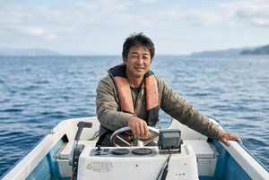 救命胴衣をつけてボートを操縦する男性