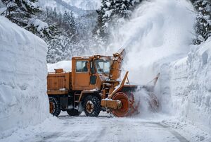 雪を飛ばして進むロータリー除雪車