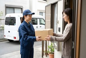 玄関先で荷物を手渡す配達員