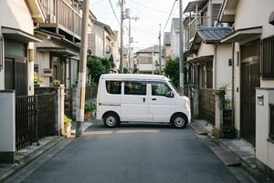 細い住宅街の道を走る配送バン