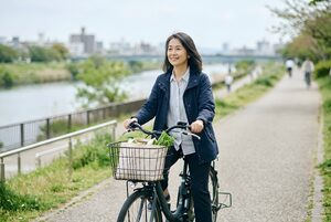 電動アシスト自転車で川沿いを走る女性