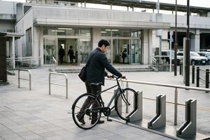 駅前のポートに自転車を返す男性