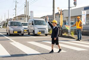 手を挙げて横断歩道を渡る小学生