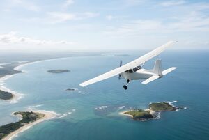 海岸線の上を旋回する小型プロペラ機